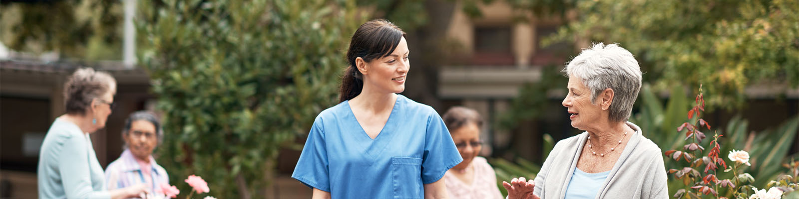 A senior woman walking outdoors with her female nursing assistant