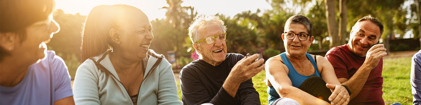 A group of senior men and women sitting outdoors while talking and laughing