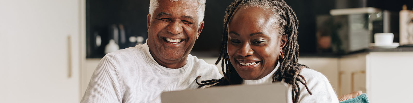 A senior man and senior woman sitting down looking at a laptop together