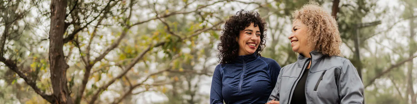 A mature woman looking over at her daughter as they walk outside in a park