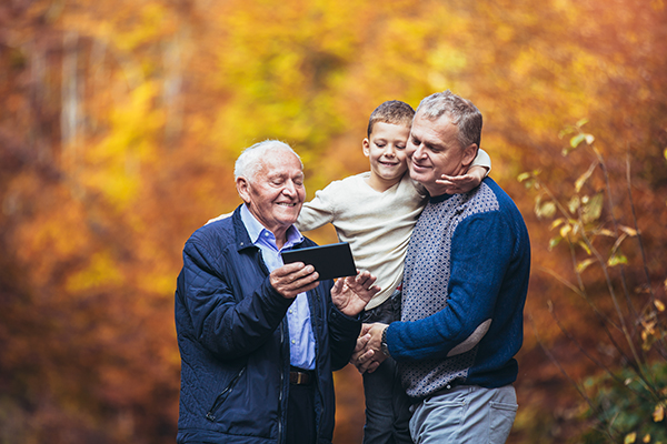 Elderly father adult son and grandson out for a walk in the park